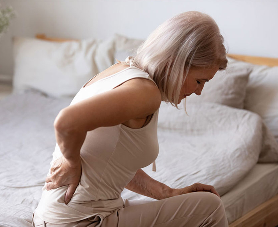 Woman sitting on her bed in pain from lumbar injury